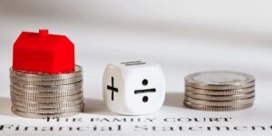 image of a monopoly hotel sitting on coins, small amount of coins and a dice with mathematical symbols